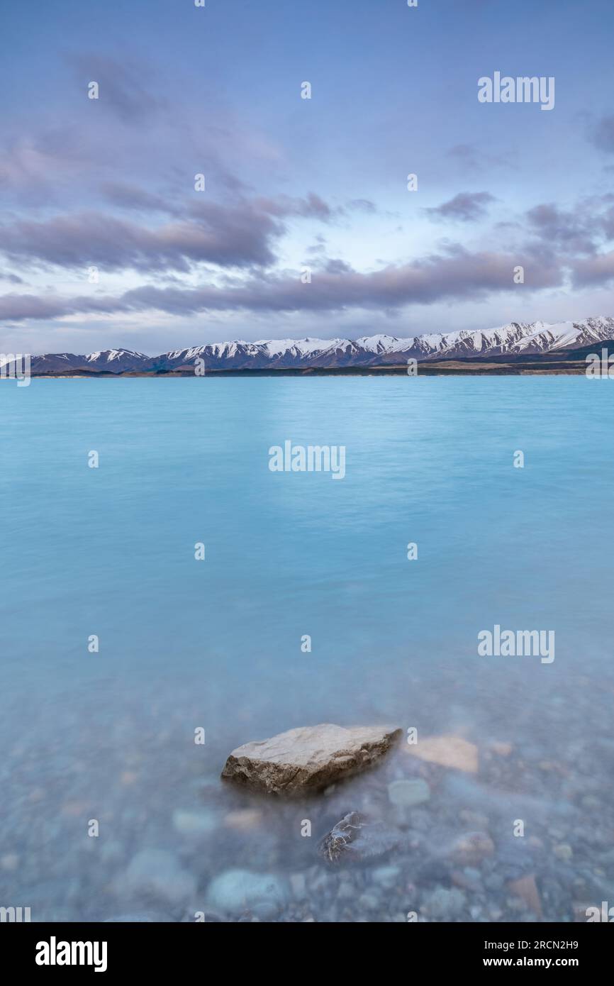 Vue panoramique au lever du soleil sur le lac Pukaki, avec leur teinte turquoise fascinante et reflétant les majestueuses Alpes du Sud enneigées. Banque D'Images