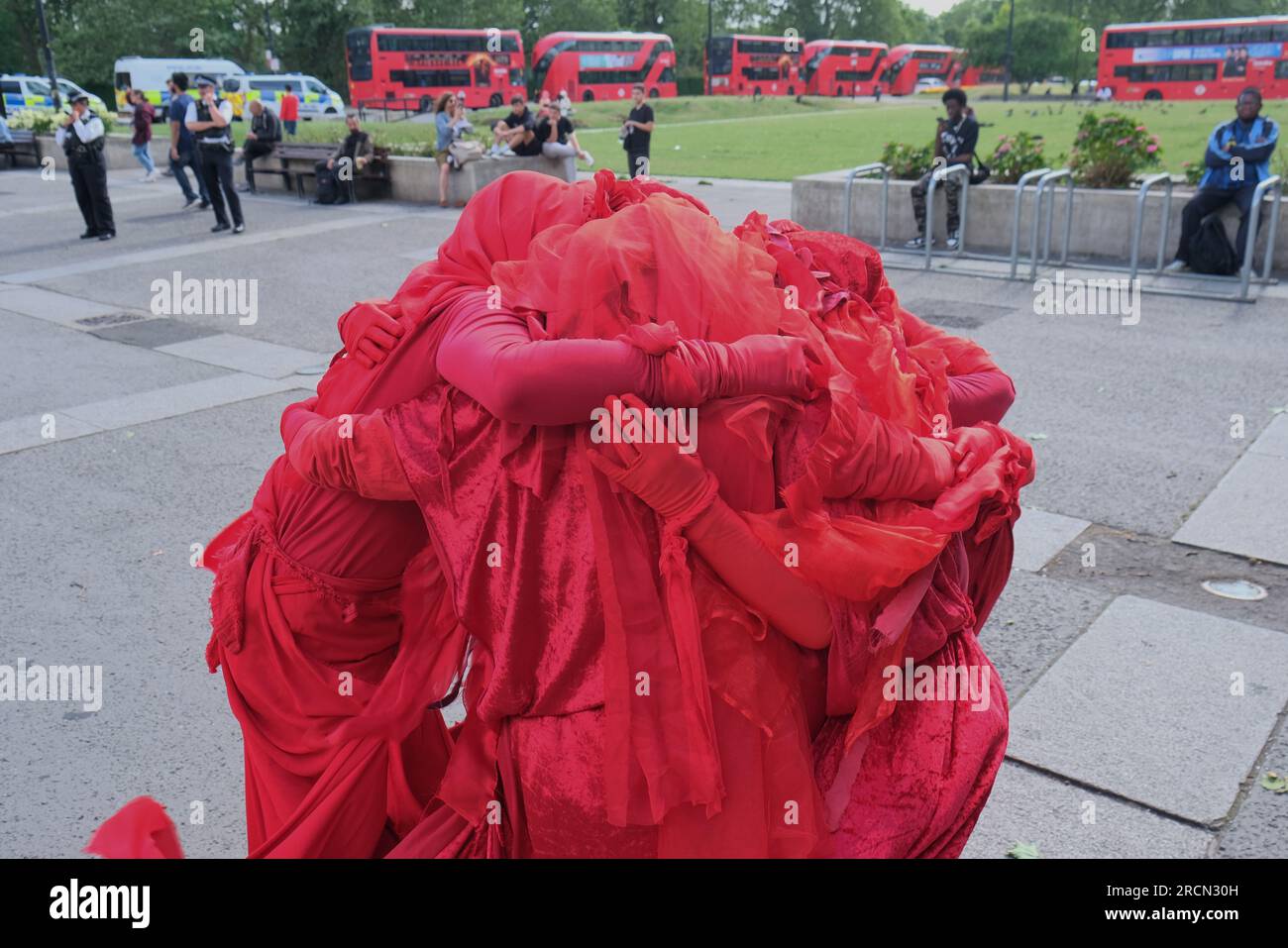 Londres, Royaume-Uni. 15 juillet 2023. Les Red Rebels se blottissent alors qu'ils tiennent une réunion. Les militants du climat de Fossil Free London, Just Stop Oil et d'autres, se sont réunis pour marcher contre le projet pétrolier et gazier de Rosebank, dirigé par le géant énergétique norvégien Equinor. Rosebank est le plus grand champ pétrolier non développé du Royaume-Uni, situé en mer du Nord et fait face à des retards dans son approbation. Crédit : Photographie de onzième heure / Alamy Live News Banque D'Images