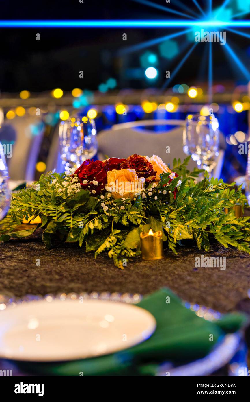 Arrangement floral de table, bouquet de roses rouges et blanches avec paillettes dorées. Banque D'Images