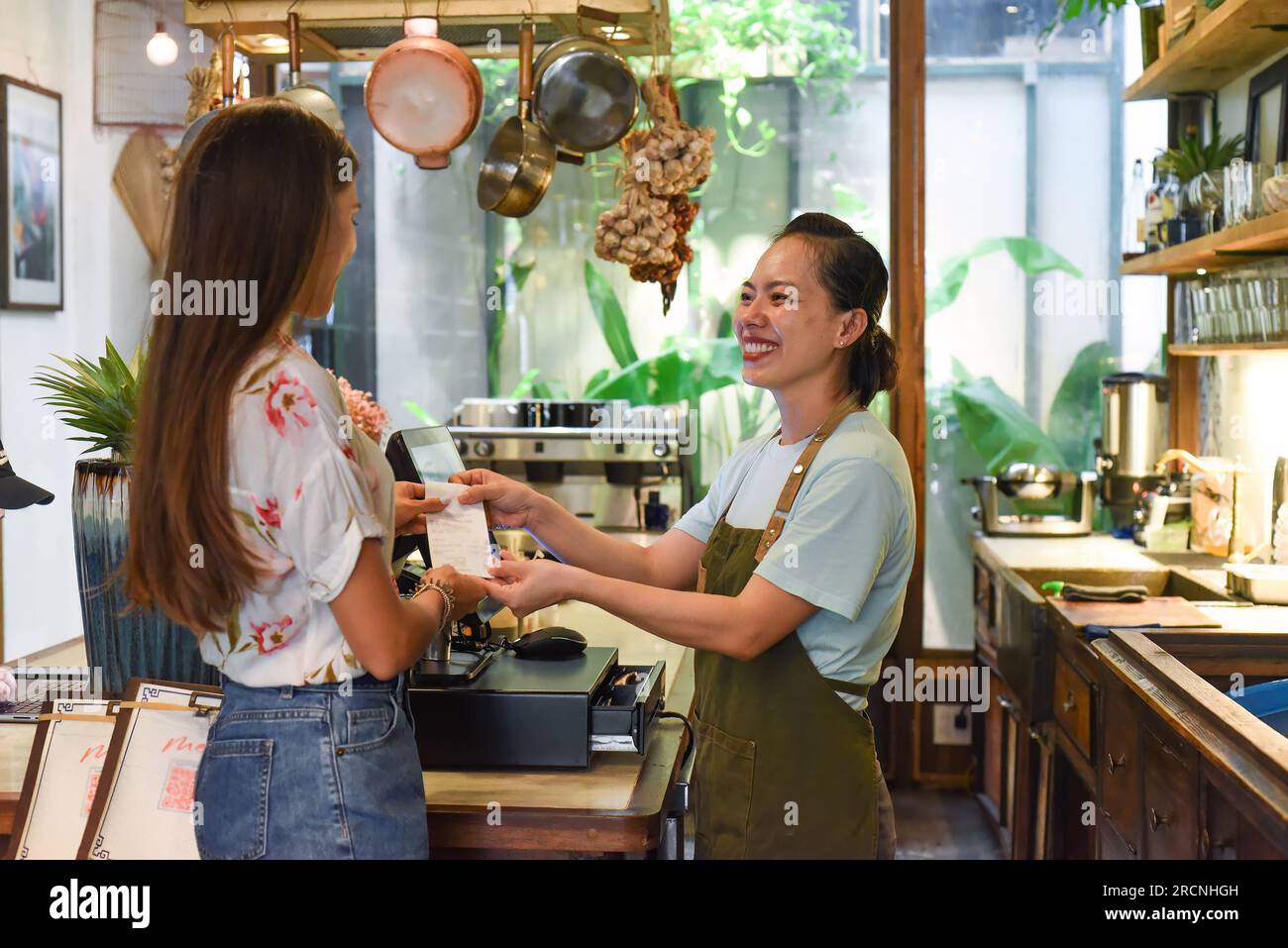 Jeune serveuse vietnamienne travaillant avec la machine de check out et les clients dans le café Banque D'Images