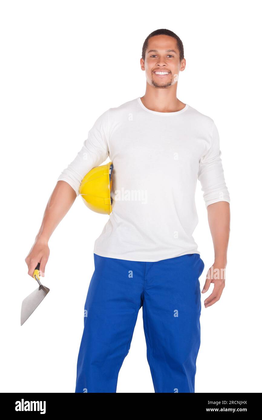 ouvrier africain de la construction en vêtements de travail , portant un casque de dur, tenant une truelle de brique isolée sur blanc Banque D'Images