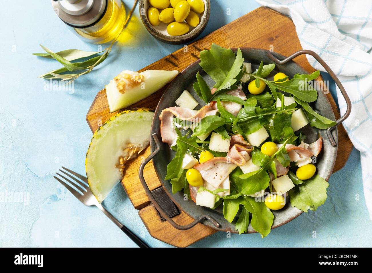 Salade méditerranéenne d'été avec melon, bacon, olives, fromage blanc et roquette sur fond de pierre bleue. Apéritif traditionnel espagnol et italien. VI Banque D'Images