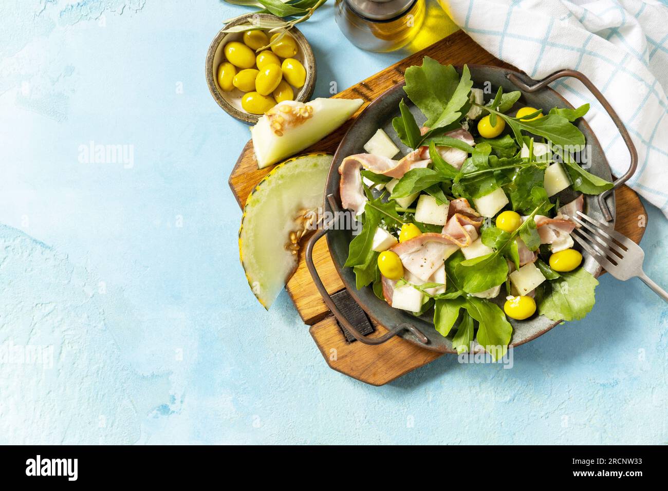 Apéritif traditionnel espagnol et italien. Salade méditerranéenne d'été avec melon, bacon, olives, fromage blanc et roquette sur fond de pierre bleue. VI Banque D'Images