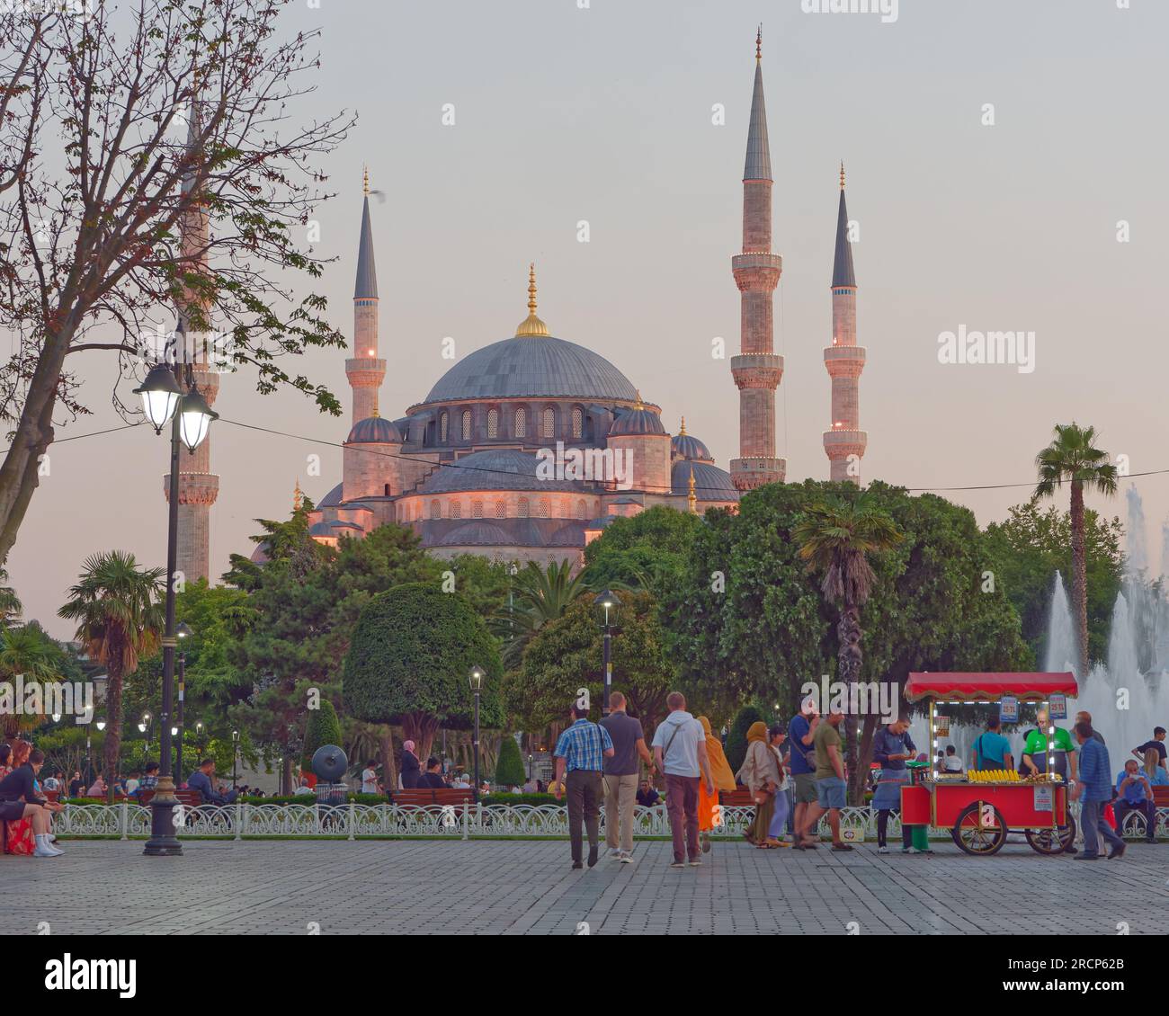 Soirée estivale avec la mosquée Sultan Ahmed aka Mosquée Bleue derrière les jardins, les touristes et une charrette rouge vendant cor. Istanbul, Turquie Banque D'Images