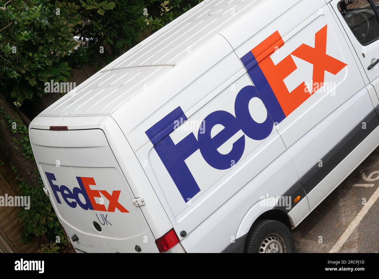 Fourgon de livraison blanc FedEx avec logo FedEx et décoration garé devant une maison en Angleterre. Thème : envois b2b, livraison express, livraison de colis Banque D'Images