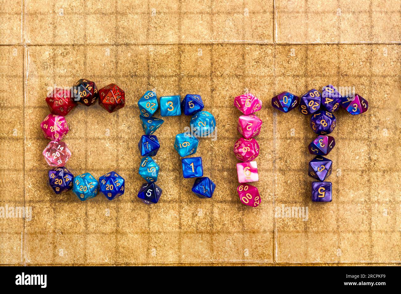 Vue aérienne de dés colorés épelant « crit » sur un jeu de rôle. Banque D'Images