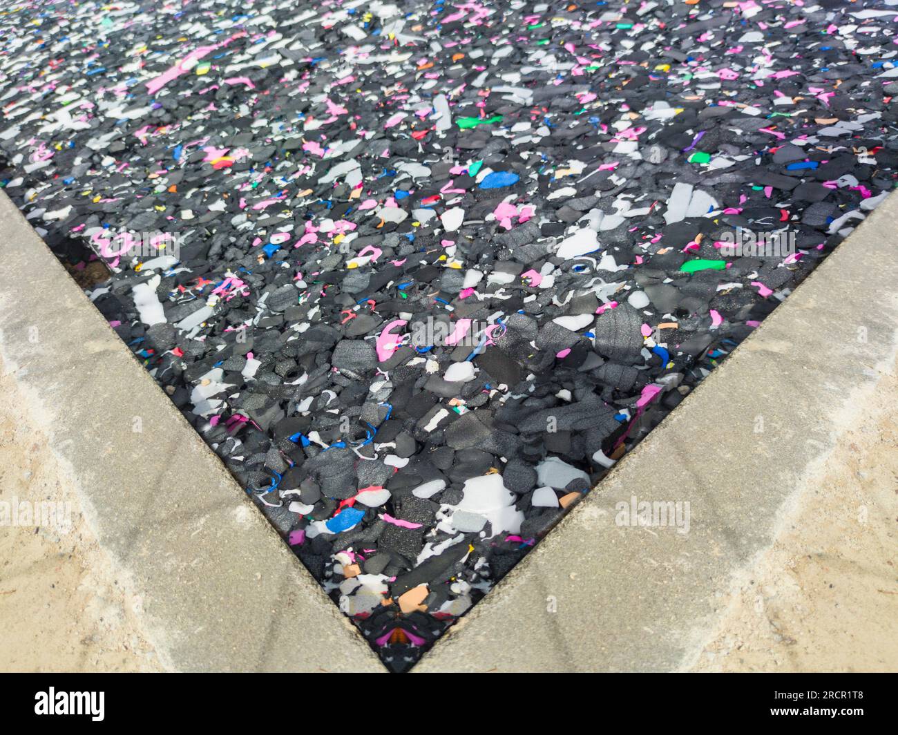 Revêtement de sol fabriqué à partir de particules de caoutchouc recyclées. Plancher de coussin noir avec des particules multicolores Banque D'Images