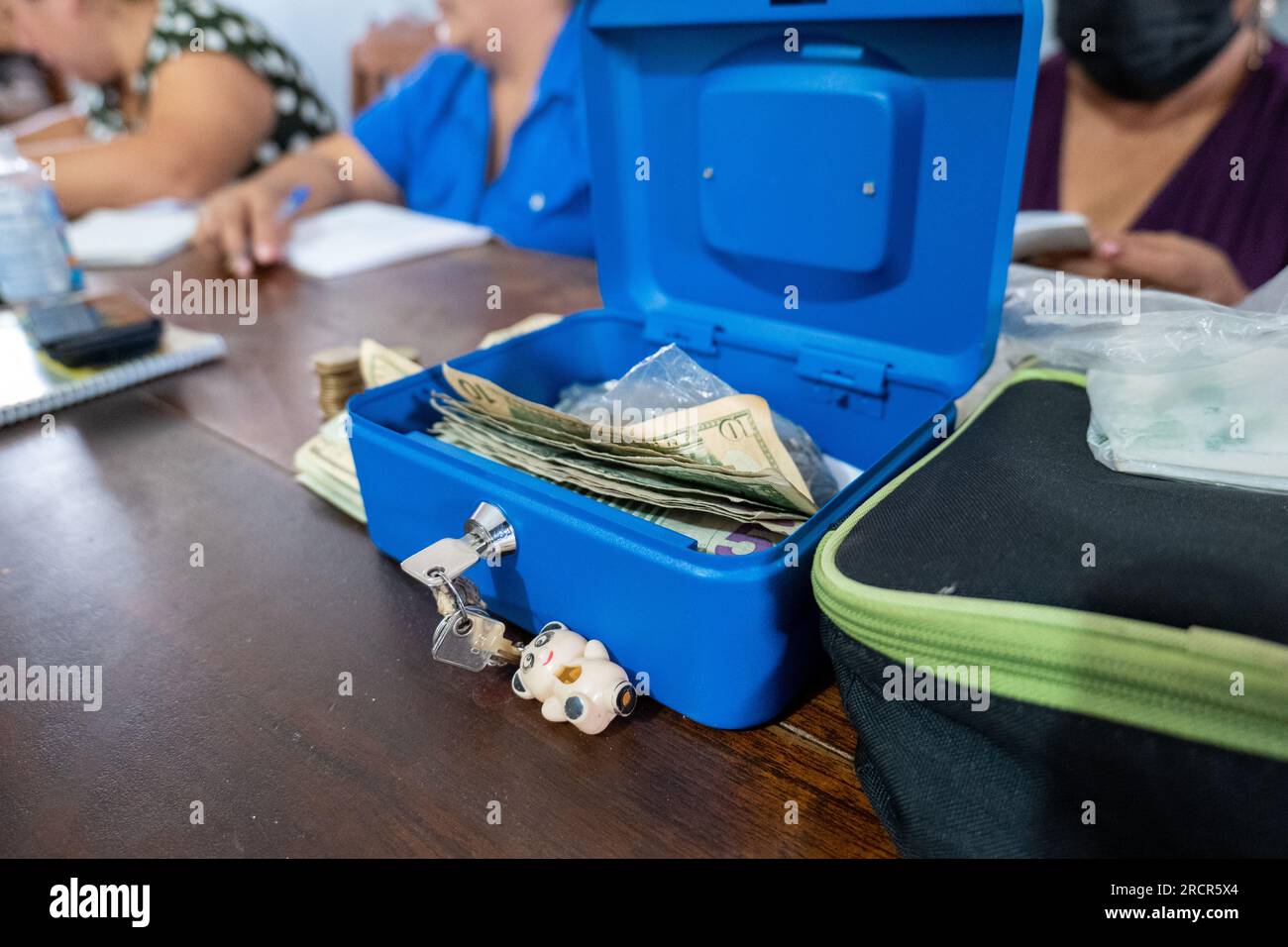 El Espino, la Libertad, El Salvador - octobre 11 2022 : les femmes salvadoriennes se sont rassemblées à une table avec une boîte en métal bleu des États-Unis Dollars Banque D'Images