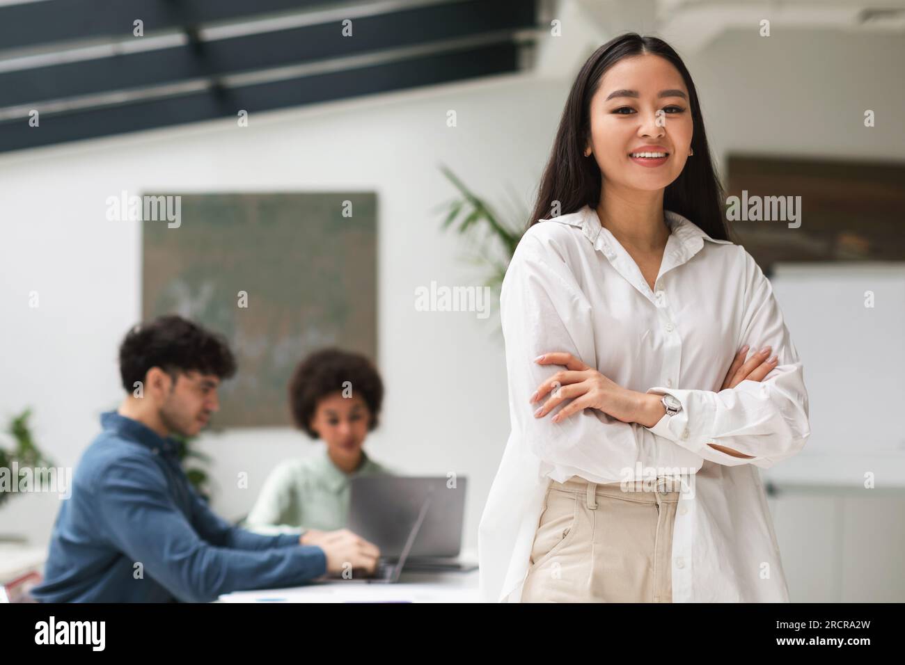 Heureuse dame d'affaires japonaise exprimant la confiance debout dans le bureau de Coworking Banque D'Images