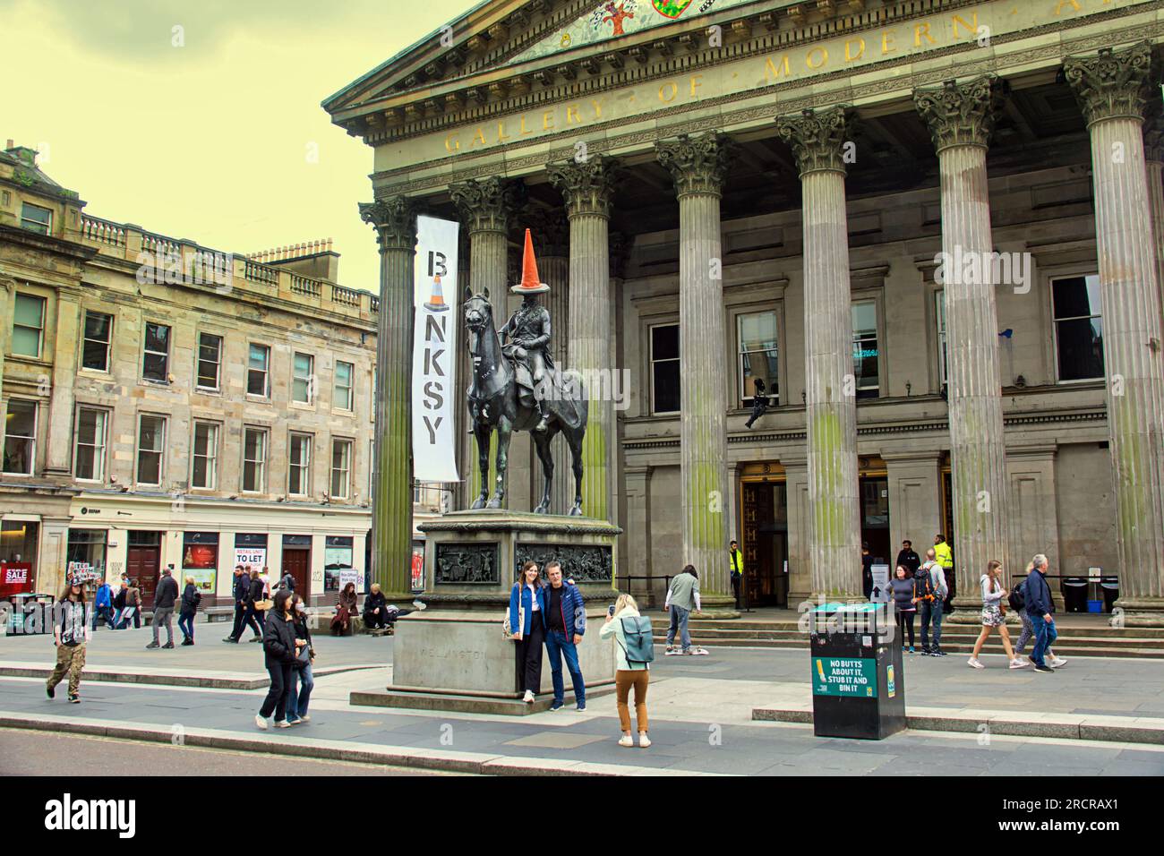 Glasgow, Écosse, Royaume-Uni 16 juillet 2023. L'homme de tête de cône l'objet de l'exposition bankys a un suivi lui-même. Visiteurs à l'extérieur du musée d'art moderne à l'exposition Banksy . New Banksy ou Wanksy comme ceux-ci sont appelés à Glasgow car leur authenticité est en doute au même endroit que celui qui a causé une telle controverse il y a quelques semaines, un pochoir parmi les graffitis post rat près de l'exposition actuelle de Cut and Run. Crédit Gerard Ferry/Alamy Live News Banque D'Images