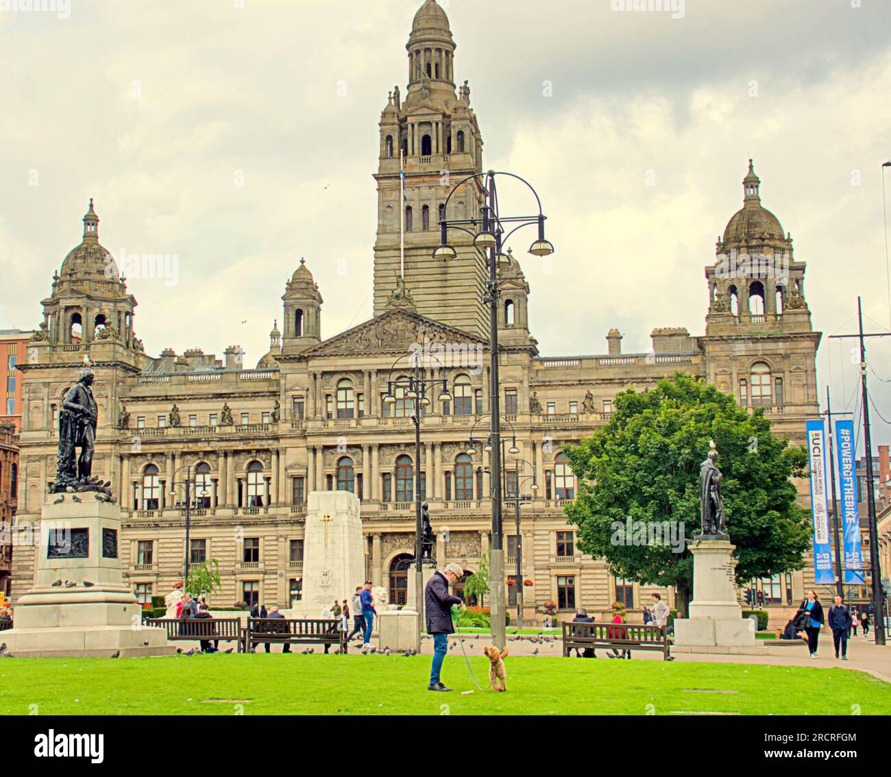 Glasgow, Écosse, Royaume-Uni 16 juillet 2023. UK Météo : temps chaud et humide et une sensation générale de dystopie ont vu les gens prendre les rues de la ville. Aman joue avec son chien devant les bâtiments du conseil. Crédit Gerard Ferry/Alamy Live News Banque D'Images