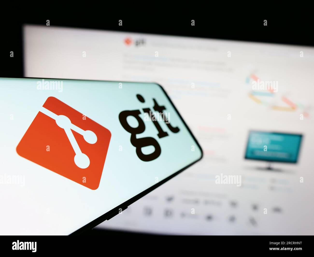 Téléphone mobile avec logo du système de contrôle de version distribué Git sur l'écran en face du site Web. Effectuez le focus sur la gauche de l'écran du téléphone. Banque D'Images