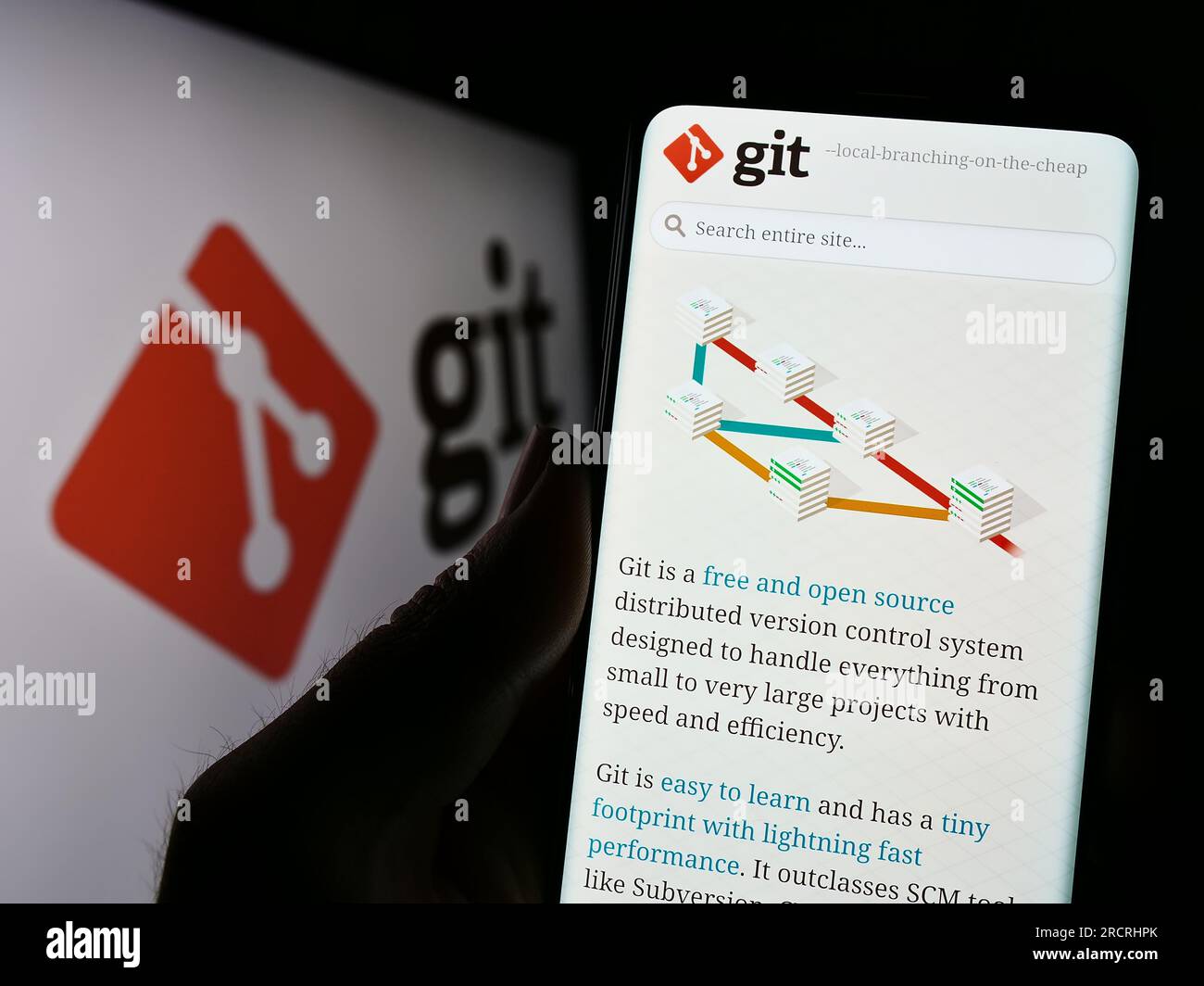 Personne tenant le téléphone portable avec la page Web du système de contrôle de version distribué Git sur l'écran en face du logo. Concentrez-vous sur le centre de l'écran du téléphone. Banque D'Images