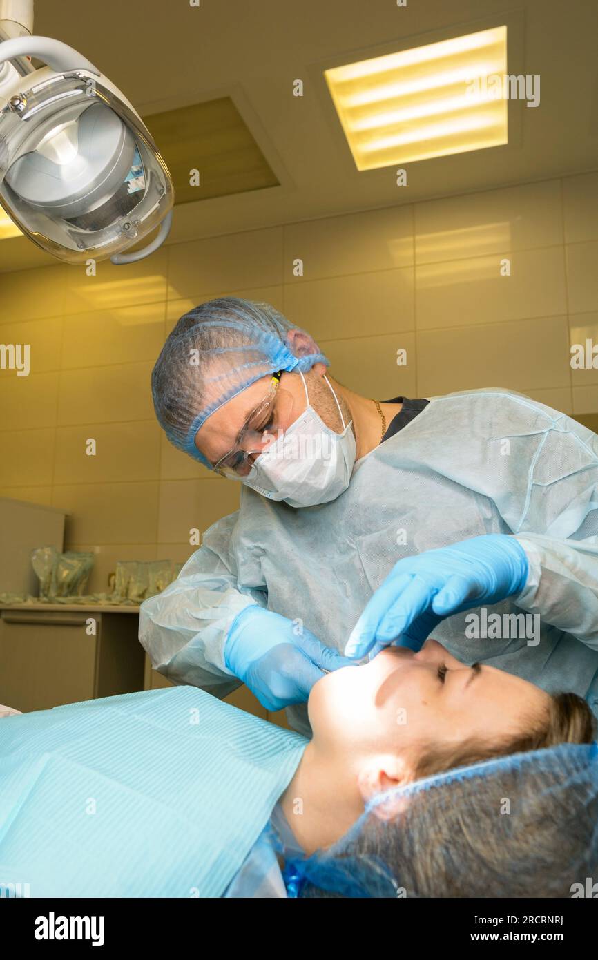 Le chirurgien-dentiste examine la bouche du patient avant d'enlever la dent de sagesse, la troisième molaire maxillaire. Procédure réelle Banque D'Images