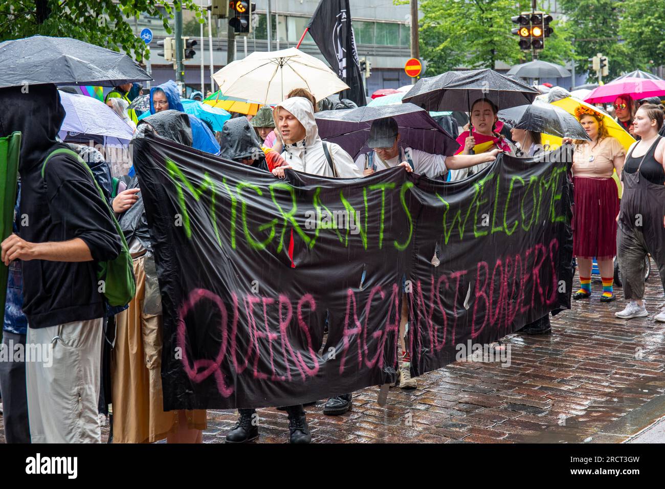 Migrants bienvenus. Queers contre les frontières. Bannière lors du défilé Helsinki Pride 2023 un jour de pluie à Helsinki, Finlande. Banque D'Images