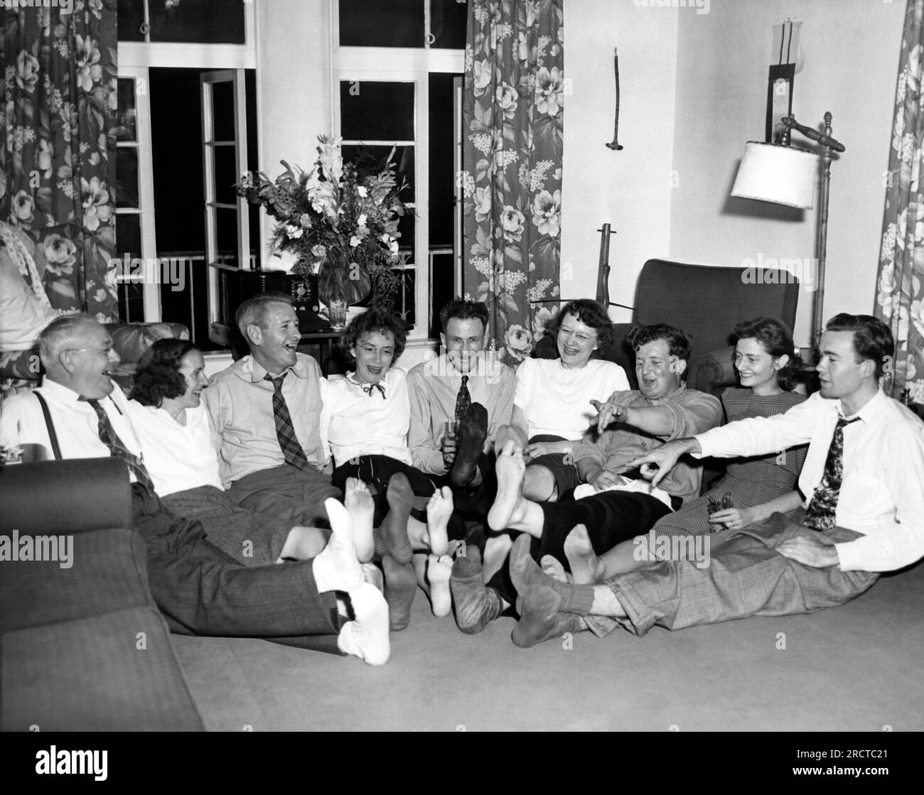 États-Unis : 1954 neuf adultes pieds nus assis sur le sol, les pieds au milieu. Banque D'Images