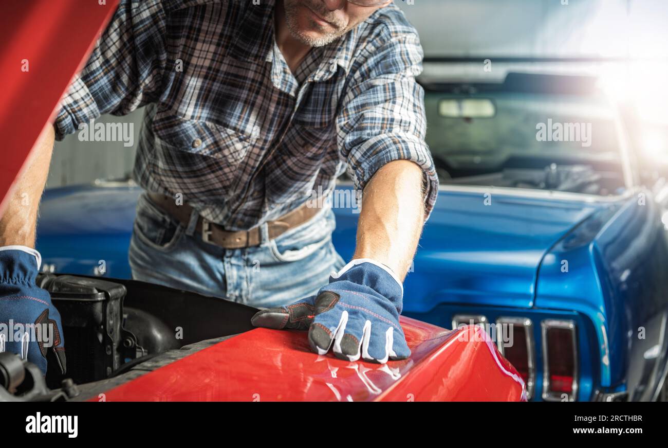Mécanicien professionnel de voitures classiques caucasiennes prenant soin des éléments d'un moteur. Thème automobile. Banque D'Images