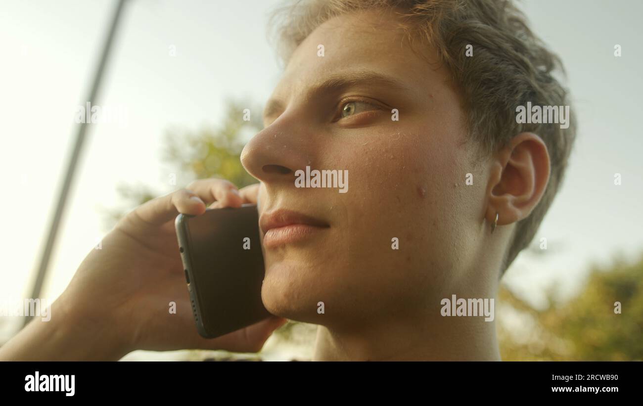 Blond Young Man répondre à un appel téléphonique et engager une conversation Banque D'Images