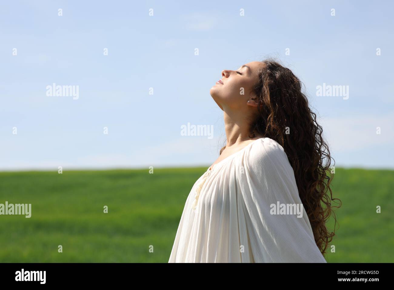Portrait vue de côté d'une femme célibataire respirant de l'air frais dans un champ vert Banque D'Images