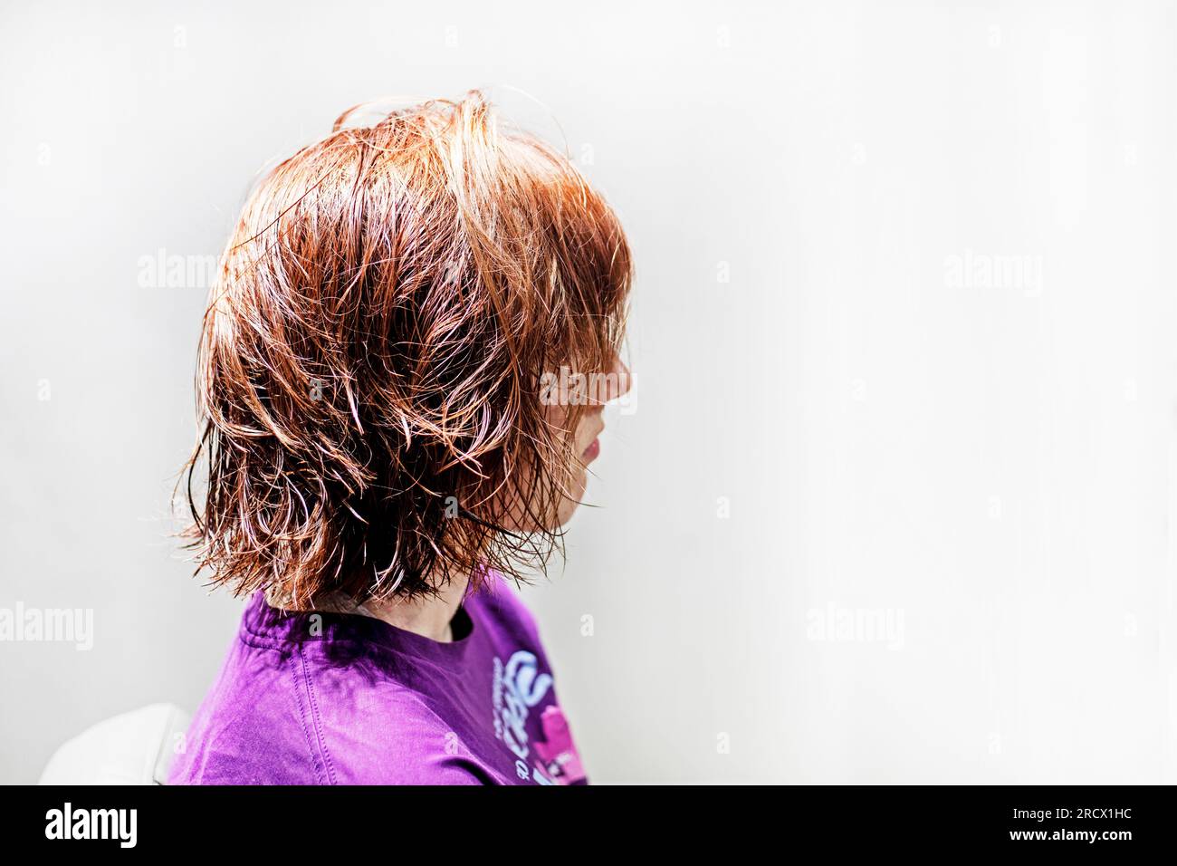 profil d'une fille teneyger avec les cheveux rouges courts mouillés après une coupe de cheveux dans un salon de beauté Banque D'Images