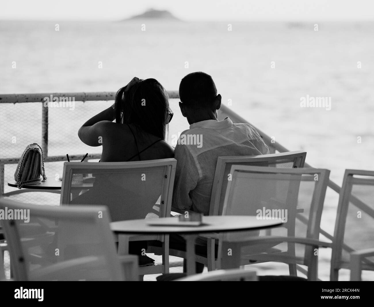 Couple d'amoureux assis embrassant dans le restaurant avec pour toile de fond la mer. Silhouettes méconnaissables datant. Coucher de soleil sur Adriatique. Ville de villégiature confortable à summ Banque D'Images