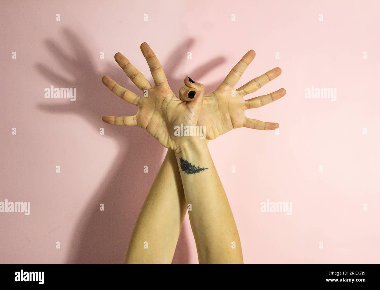 mains unies de femme avec tatouage sur fond rose Banque D'Images