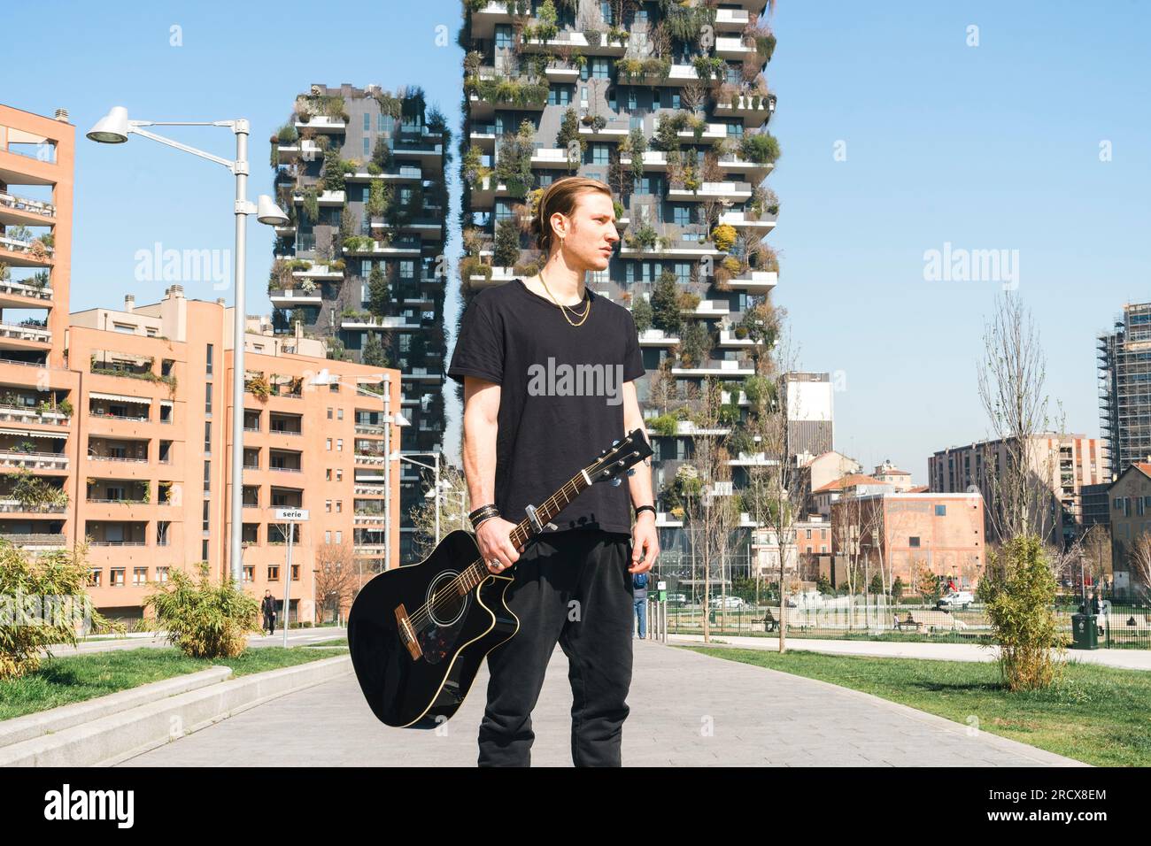 homme tenant une guitare est debout devant deux skyscreapers verts Banque D'Images homme tenant une guitare est debout devant deux skyscreapers verts Banque D'Images
