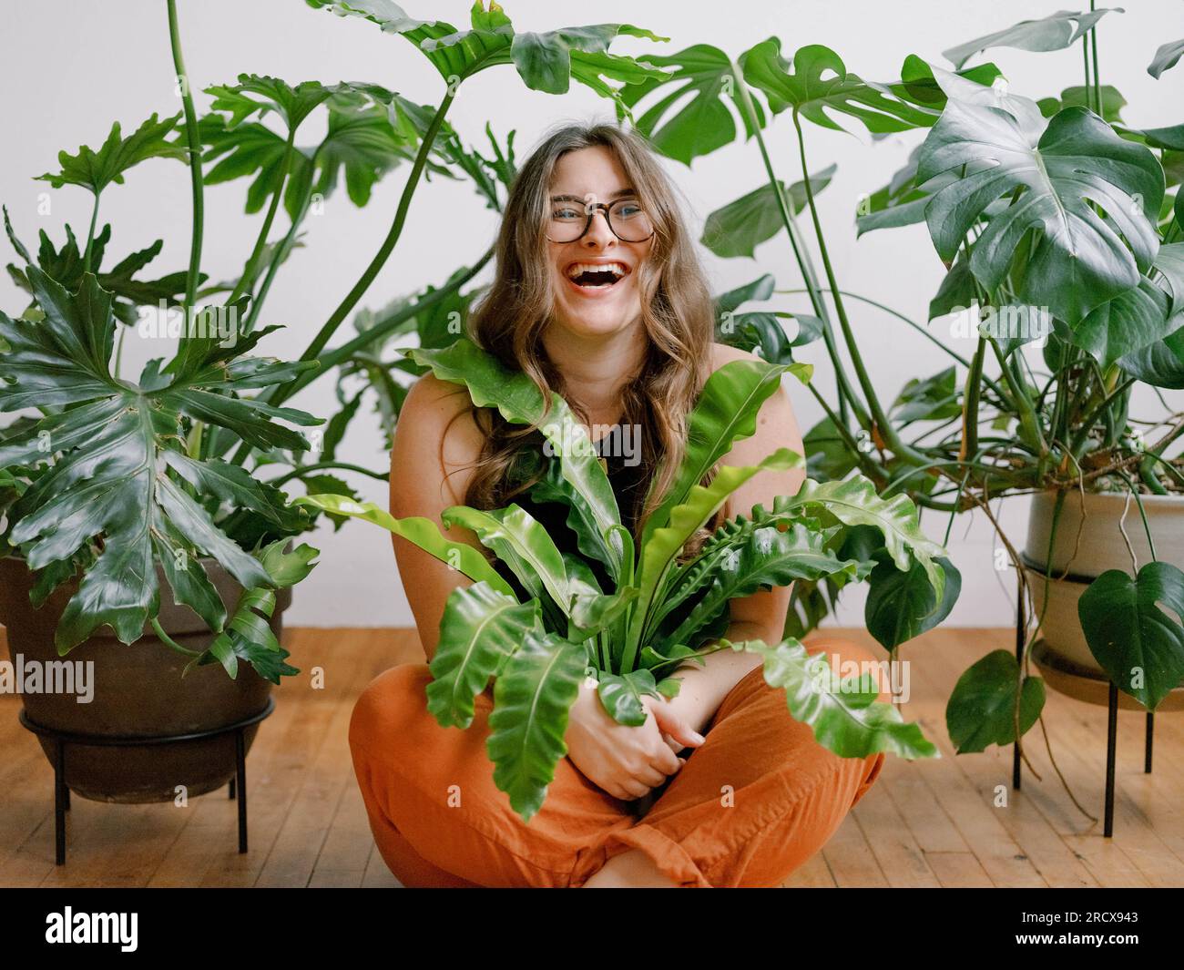 Joyeuse femme millénaire embrassant les plantes d'intérieur vertes Banque D'Images