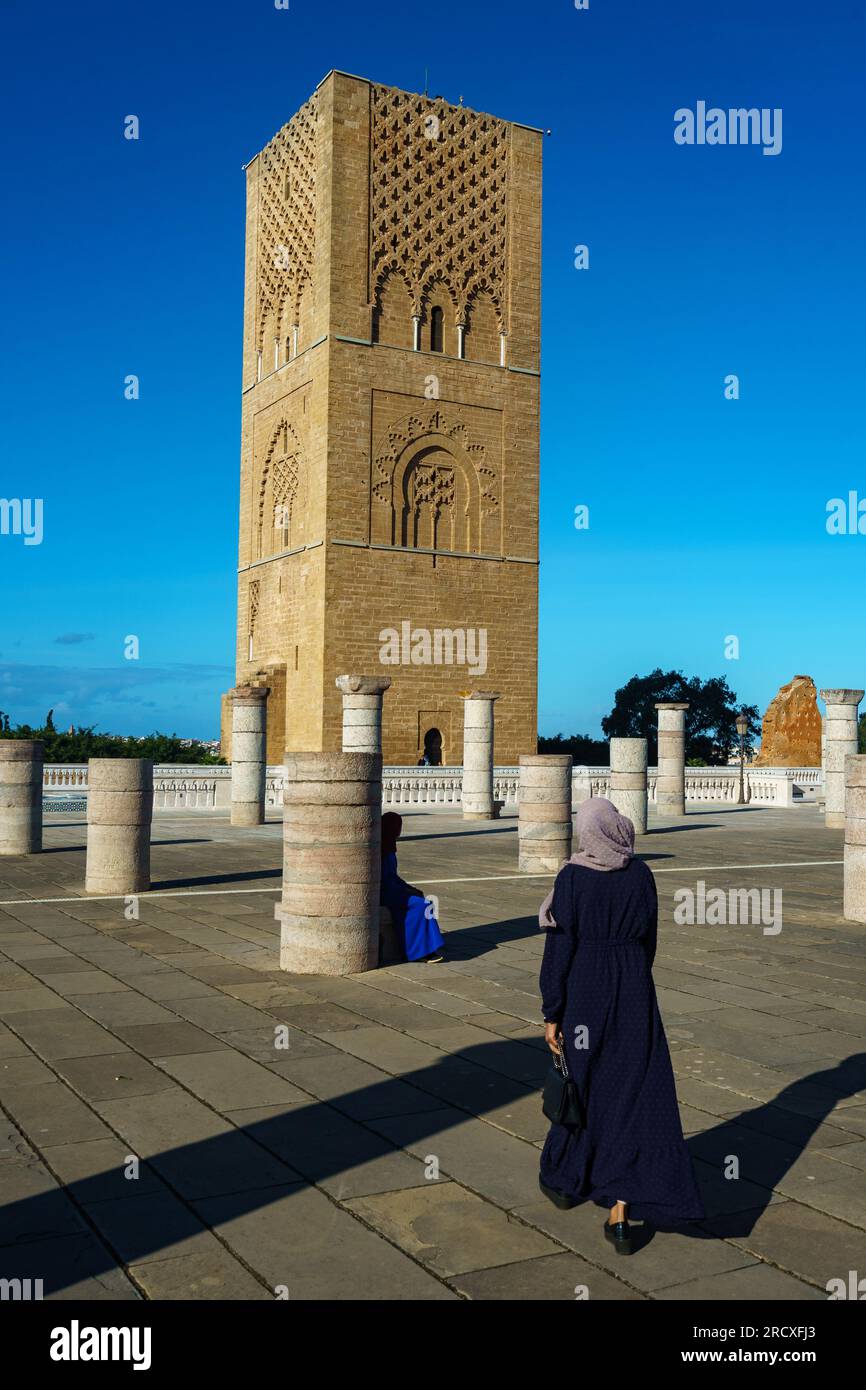 Maroc. Rabat. Une femme se promène devant la magnifique Tour Hassan et ses colonnes de pierre sur l’esplanade de Yacoub al-Mansour. La tour est incomplète Banque D'Images