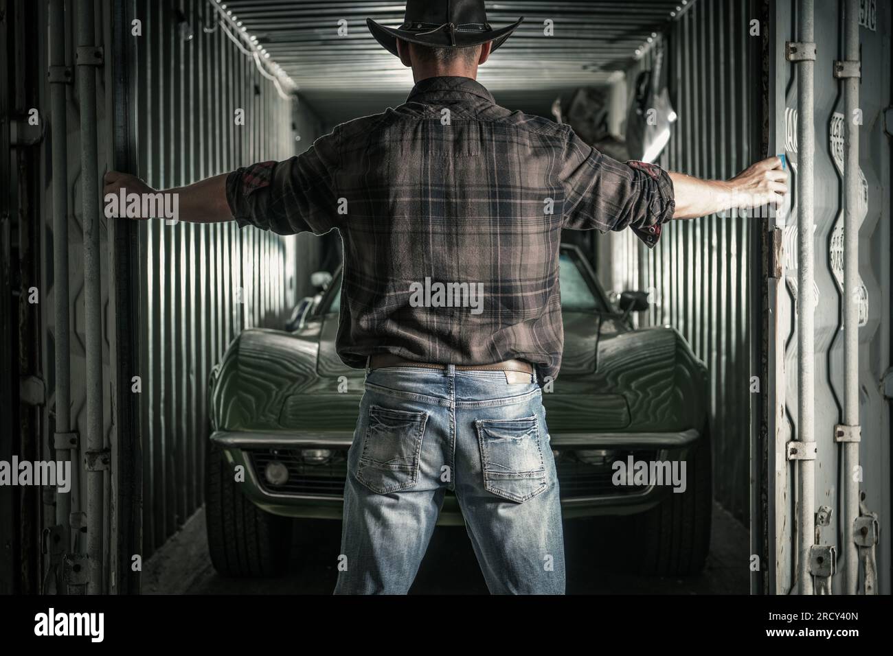 Caucasian Cowboy dans ses années 40 ouverture de son stockage avec muscle Classic Cars à l'intérieur. Prêt à démarrer le projet. Banque D'Images