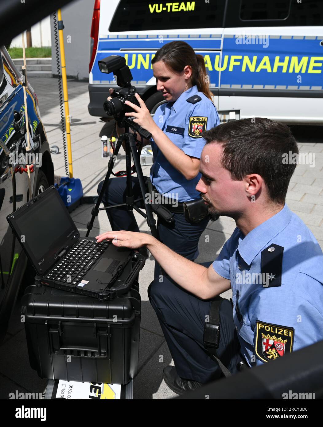 Mayence, Allemagne. 17 juillet 2023. Julia Kurz (arrière), commissaire de police, et Dominik Knopp, commissaire de police, de l'équipe d'enregistrement des accidents de la circulation montrent dans la cour du ministère de l'intérieur comment lire l'interface OBD d'une voiture et enregistrer les dommages à l'aide d'un appareil photo numérique. La police de Rhénanie-Palatinat prévoit de déployer des équipes pour enregistrer les accidents de la circulation dans l'État en utilisant une technologie numérique spéciale. En plus de la formation professionnelle spéciale, les équipes disposeront d'un équipement technique spécial. Crédit : Arne Dedert/dpa/Alamy Live News Banque D'Images