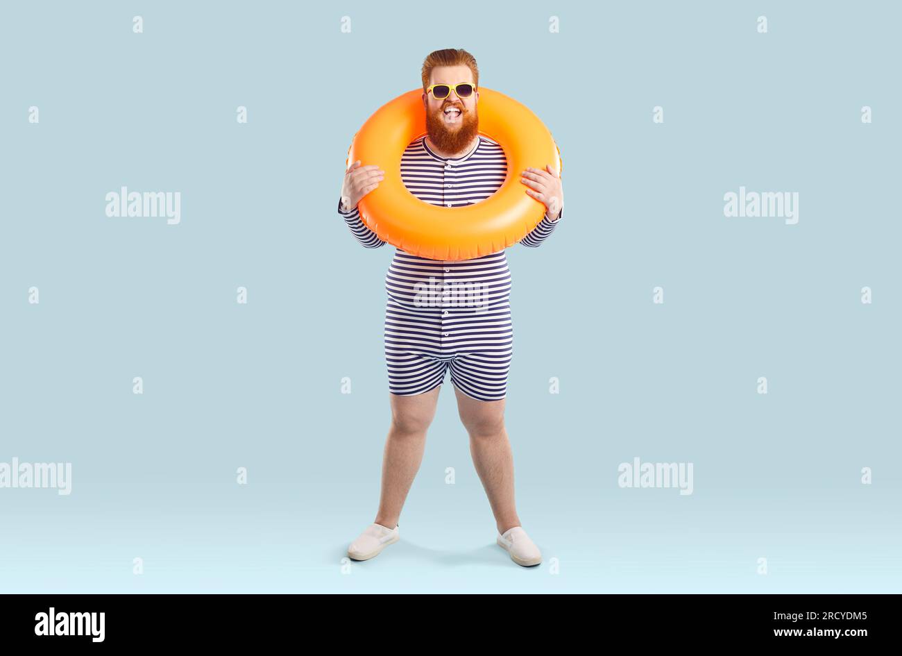 Portrait de nageur masculin drôle gras en maillot de bain rayé et avec cercle gonflable autour de son cou. Banque D'Images