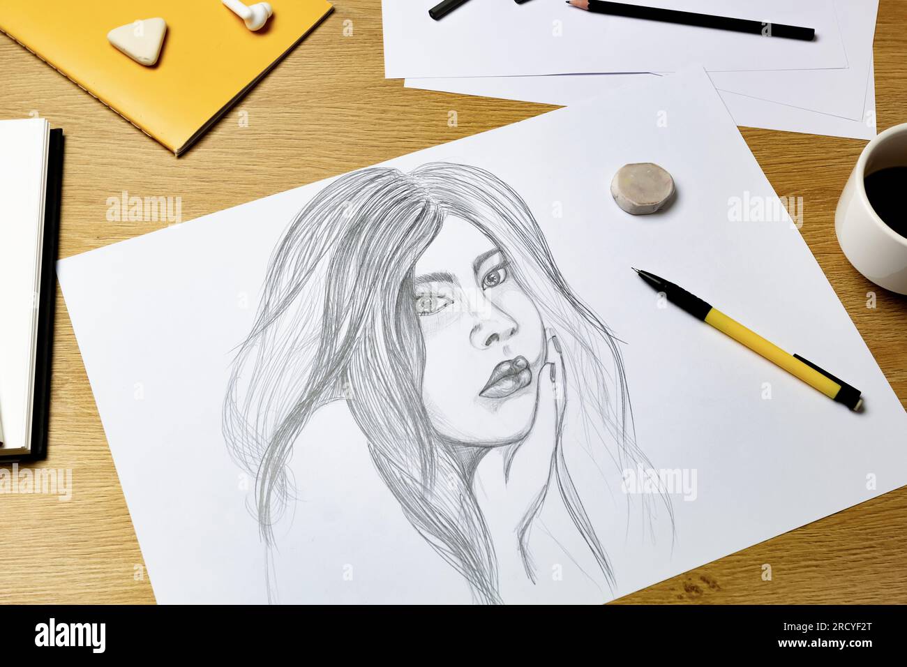 L'artiste dessine un portrait d'une femme avec un crayon sur du papier blanc. Banque D'Images