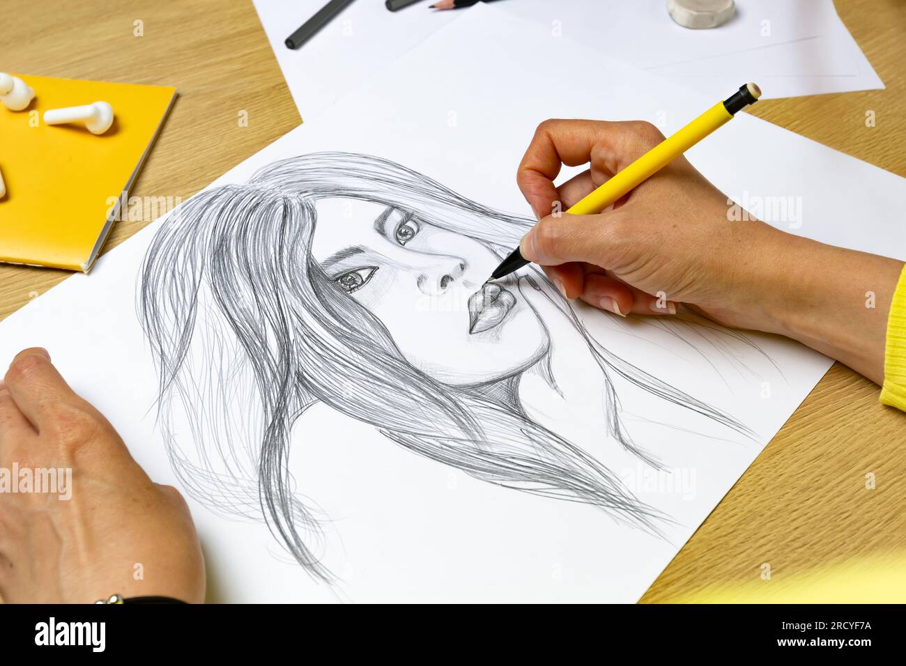 L'artiste dessine un portrait d'une femme avec un crayon sur du papier blanc. Banque D'Images