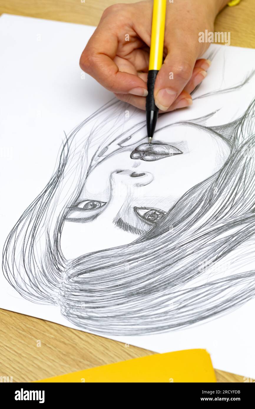 L'artiste dessine un portrait d'une femme avec un crayon sur du papier blanc. Banque D'Images