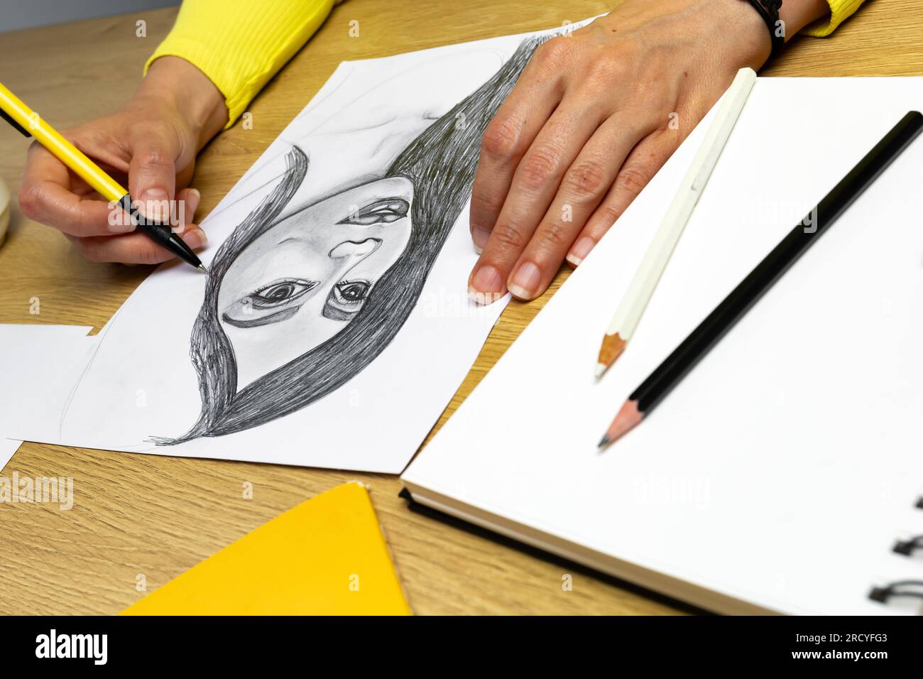 L'artiste dessine un portrait d'une femme avec un crayon sur du papier blanc. Banque D'Images