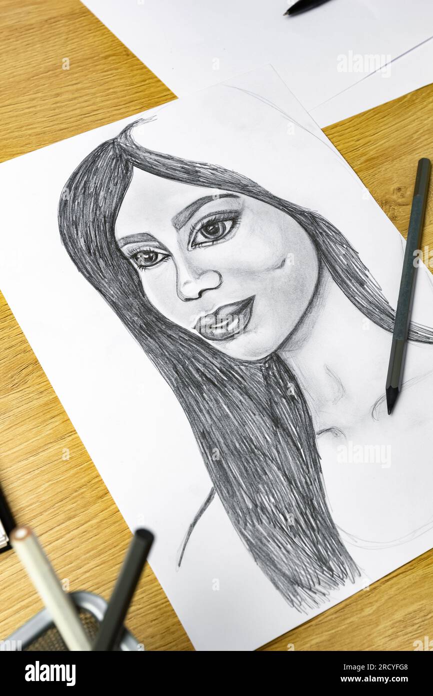 L'artiste dessine un portrait d'une femme avec un crayon sur du papier blanc. Banque D'Images