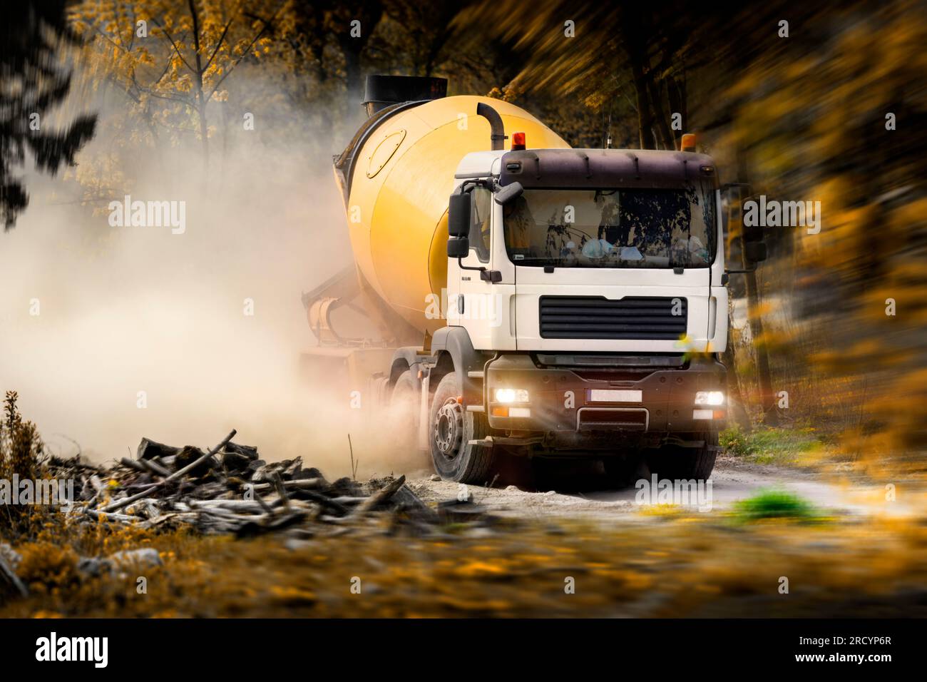 Un camion, un malaxeur de béton, se précipitant le long d'une route de gravier, jetant des nuages de poussière dans l'air.développement des espaces verts. Croissance urbaine et investissement. Banque D'Images