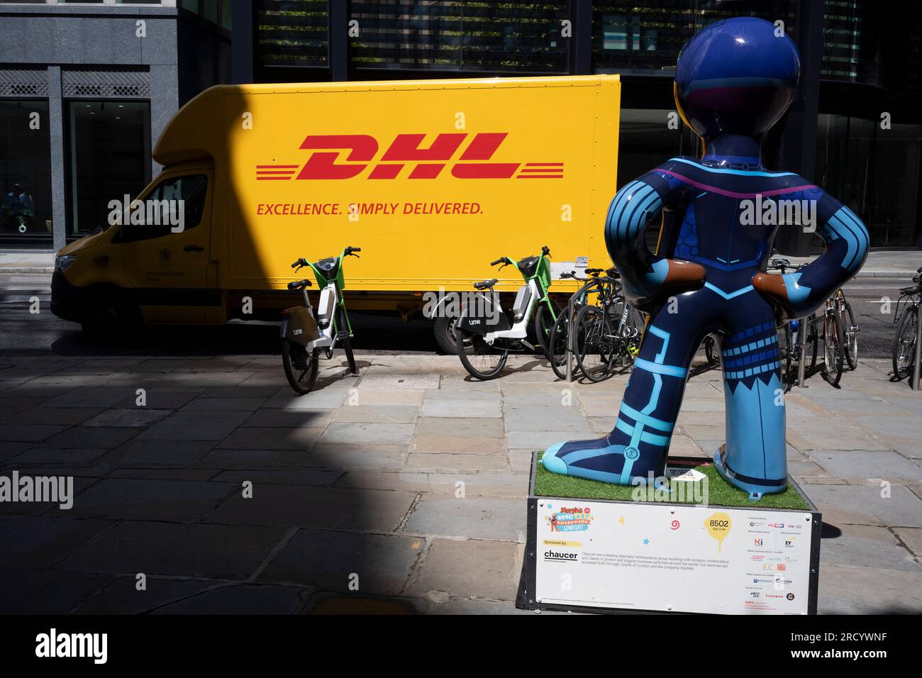 Un camion de livraison DHL jaune est garé et une œuvre d'art sponsorisée par la marque d'assurance 'Chaucer' (qui fait partie du groupe China Re) dans la City de Londres, le quartier financier de la capitale, le 17 juillet 2023, à Londres, en Angleterre. Banque D'Images