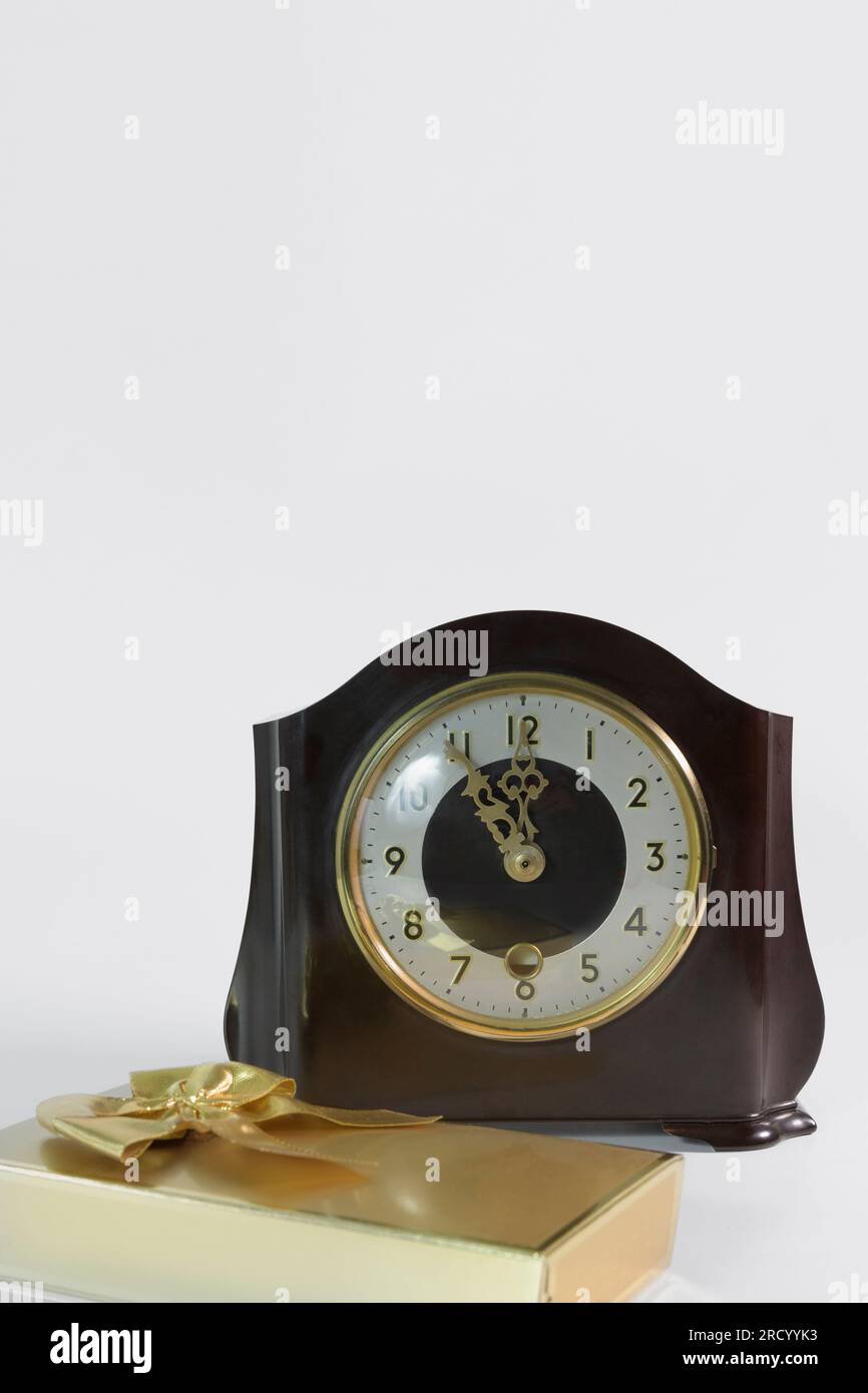 Horloge vintage de table et un cadeau dans un paquet doré avec un arc sur un fond blanc Banque D'Images