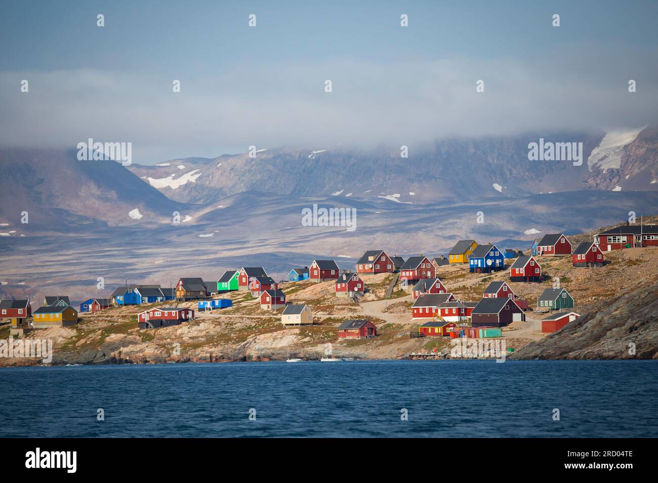 Belle vue sur un village isolé au Groenland. Maisons colorées situées sur le rivage. Montagnes et glaciers en arrière-plan. L'été arctique. Banque D'Images