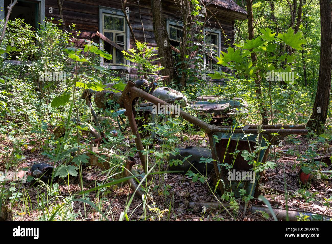 Un cadre rouillé d'une moto sur le fond d'une maison abandonnée dans la zone d'exclusion de la Biélorussie Banque D'Images