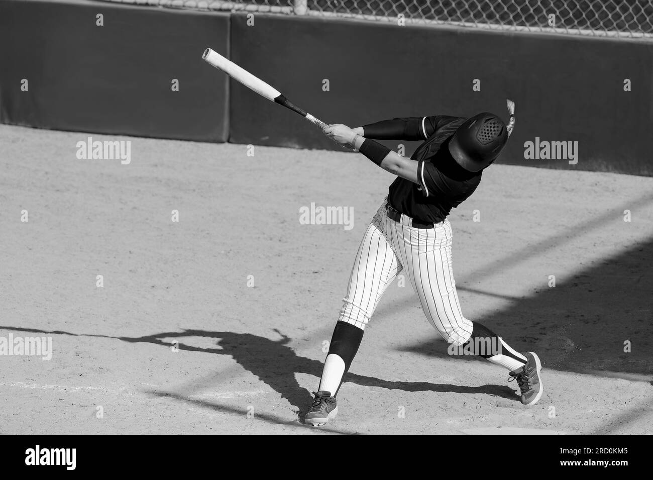 Un joueur de softball de baseball est balancer la batte frappant la balle noir et blanc Banque D'Images