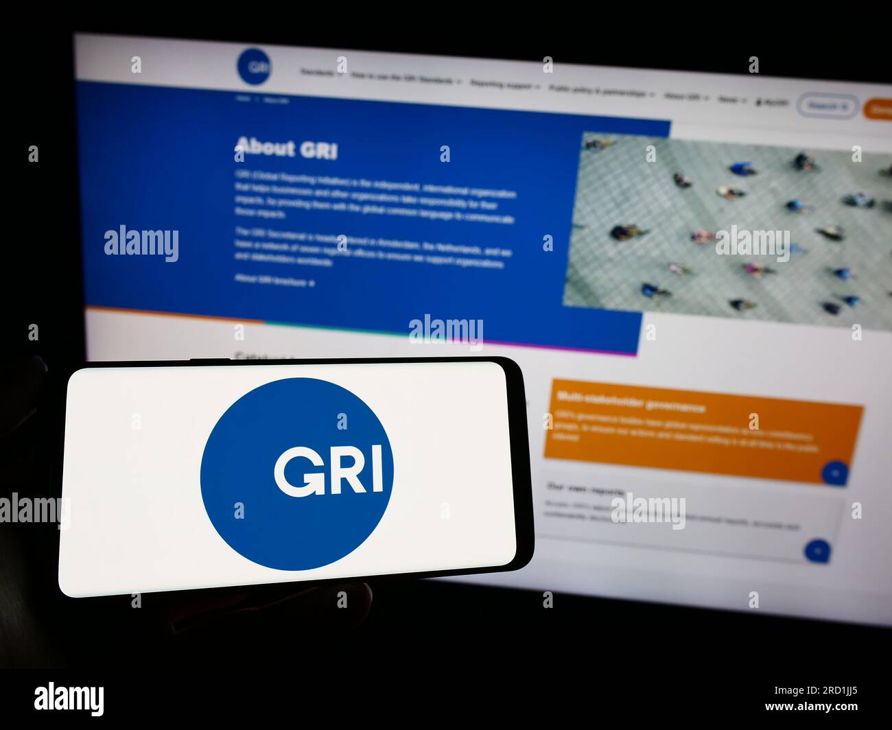 Personne tenant un téléphone intelligent avec le logo de la Global Reporting Initiative (GRI) à l'écran devant le site Web. Concentrez-vous sur l'affichage du téléphone. Banque D'Images