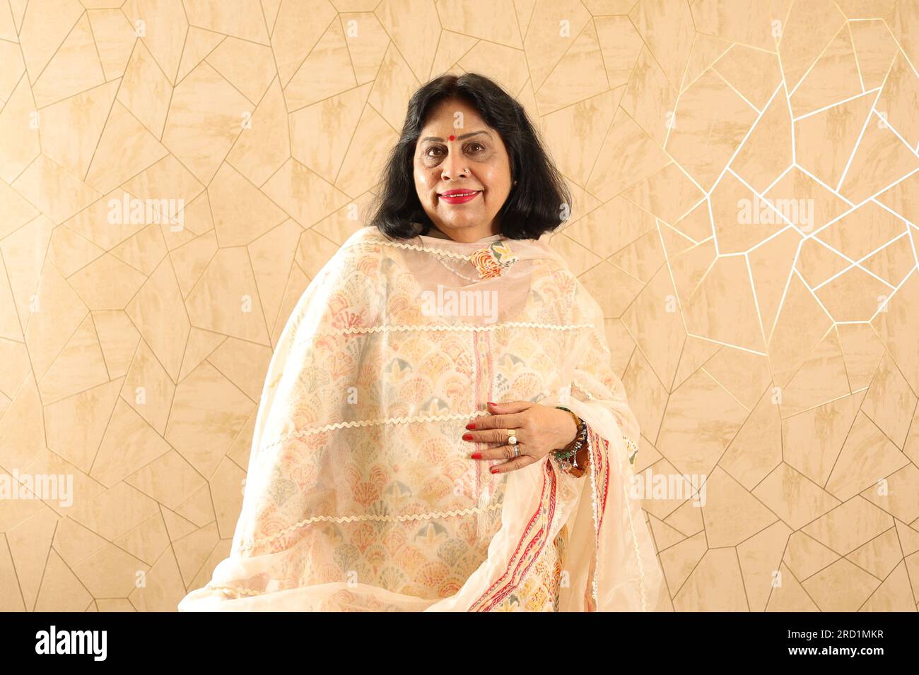 Vieille dame indienne debout avec mur. Mur de blanchissage. Beau portrait heureux de grand-mère debout contre le mur dans le salon nouvellement meublé. Banque D'Images