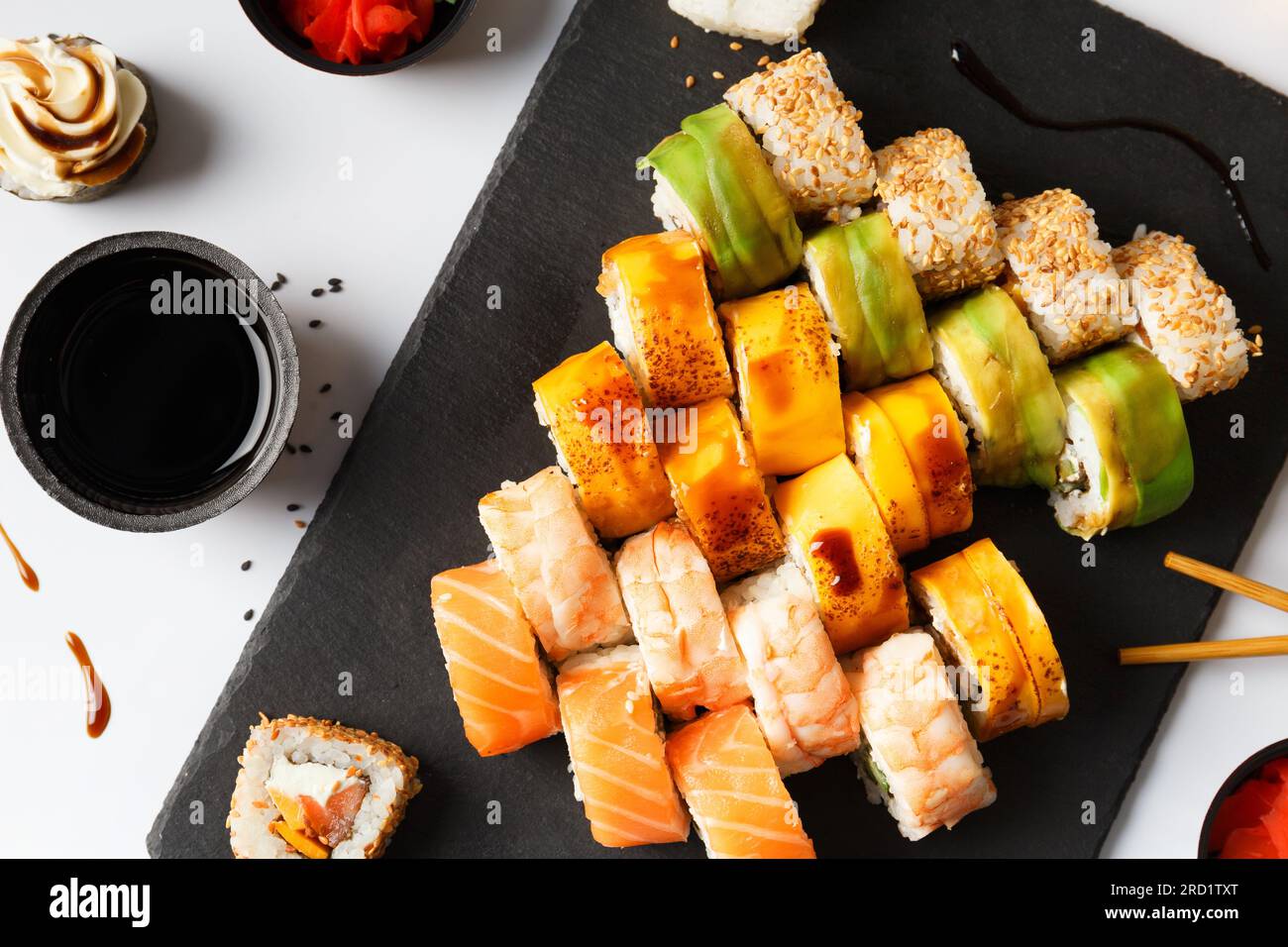 Set rouleau avec saumon, avocat, crevettes et anguille sur une planche de pierre avec wasabi et sauce soja sur un fond gris, vue de dessus Banque D'Images