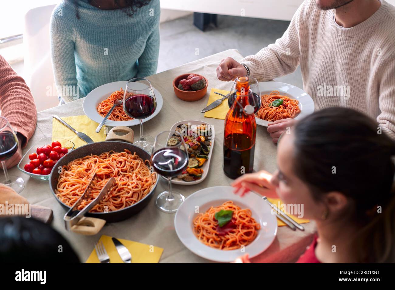 Gros plan de jeunes amis avec des fourchettes debout près de la table servie avec des pâtes maison Banque D'Images
