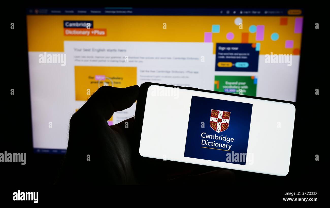 Personne tenant le téléphone portable avec le logo de Cambridge Dictionary sur l'écran en face de la page Web. Concentrez-vous sur l'affichage du téléphone. Banque D'Images