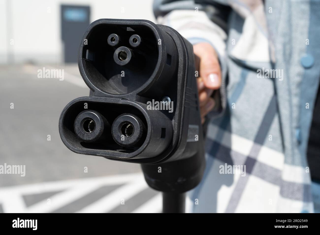 Femme tenant la prise CCS type 2. Prise de connecteur Combo 2 du système de charge combiné rapide pour véhicules électriques à la station EV. Branchement du chargeur de voiture. Banque D'Images