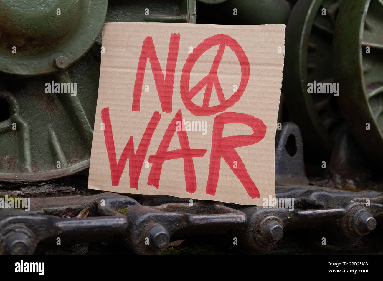 Étiquette « No War » avec symbole « Peace » sur les roues à chenilles continues Caterpillar du réservoir militaire. Véhicule militaire blindé de combat à chenilles avec bannière anti-guerre. Banque D'Images
